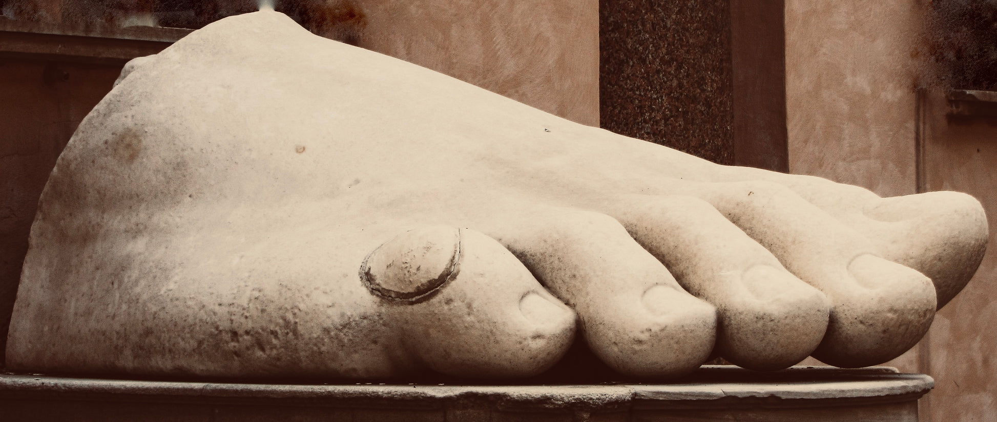 Stone sculpture of a foot with detailed toes on a pedestal